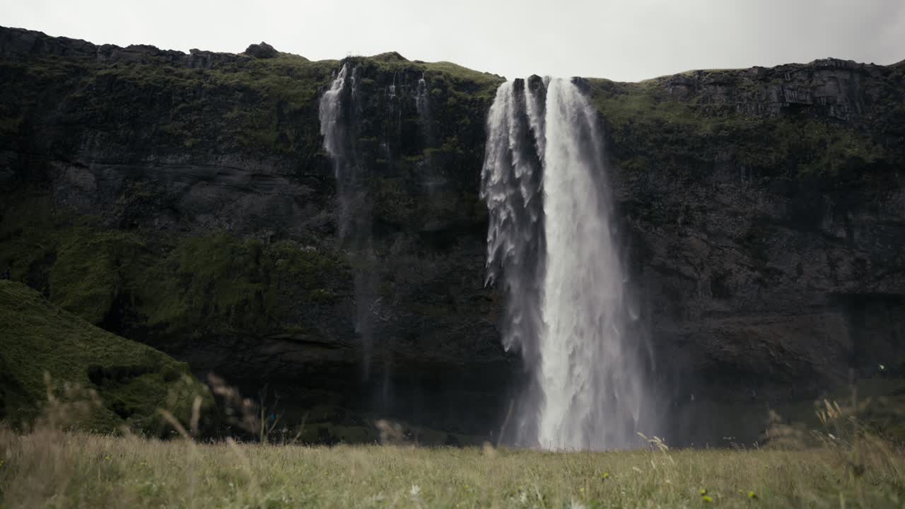 amplia toma de dolly de una escena absolutamente impresionante de una cascada, acantilados y campo verde