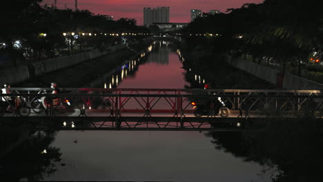 traffic on small bridge over city river at sunset