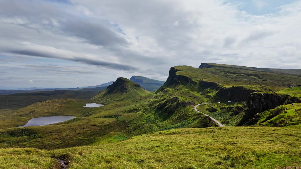Naturskøn vid udsigt over klippeklipper og en vej med udsigt over en fantastisk dal set fra Quiraing-bjerget på Isle of Sky, Skotland, på en solrig sommerdag