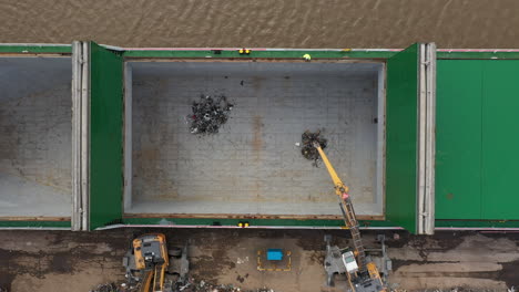 Aerial-birdseye-footage-of-mechanical-grab-machines-loading-scrap-metal-onto-a-ship