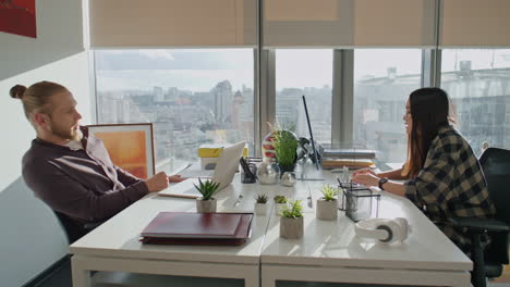 positive coworkers talking at monitor workplace close up. man gesturing to woman