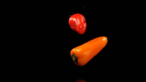 Bell-peppers-falling-on-water-against-black-background-4k