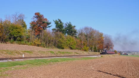 Ein-Antiker,-Restaurierter-Dampfzug,-Der-Sich-An-Einem-Sonnigen-Herbsttag-Mit-Rauch-Und-Dampf-Nähert