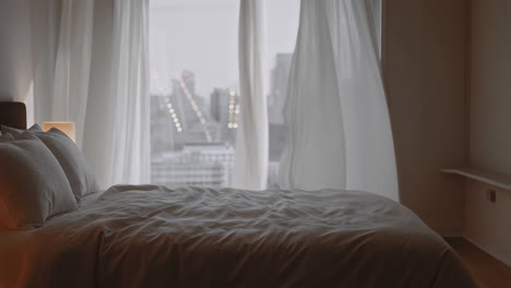 bedroom with city view and blowing curtains