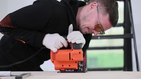 man cutting a wooden board with an electric jigsaw