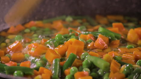 Close up Shot on Mix of Fresh Vegetables in a cooking pan with colorful combination of Green peas and Carrots with a black background and shot on 4K