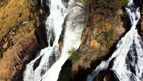 una corriente de agua que fluye por rocas africanas creando una pequeña cascada en la presa de hartebeesport, noroeste, sudáfrica