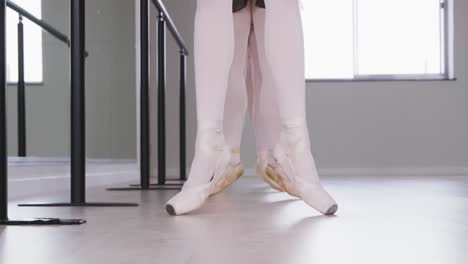 Caucasian-ballet-female-dancers-stretching-up-with-a-barre-before-a-ballet-class