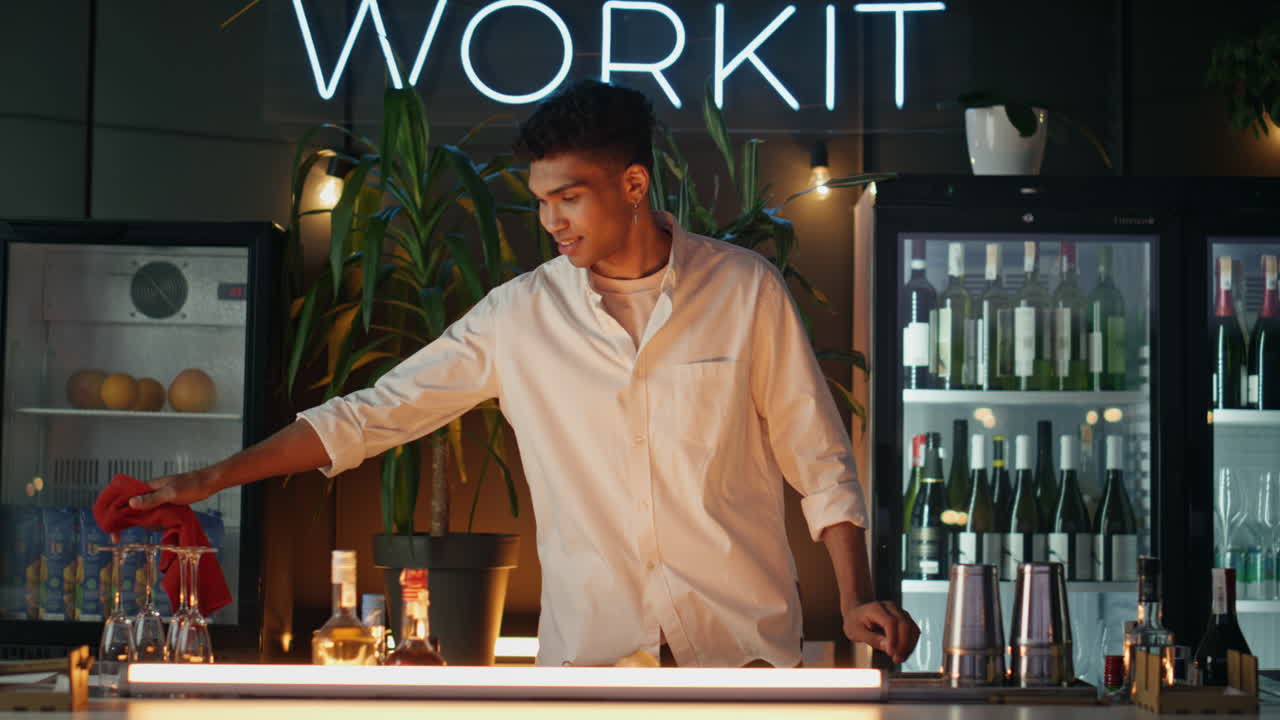 hombre positivo limpiando platos en el mostrador del bar del café. barista de piel negra mirando la cámara