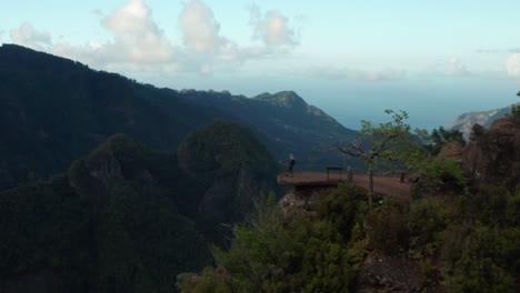 lone female traveler walks to edge of viewpoint to enjoy amazing landscape