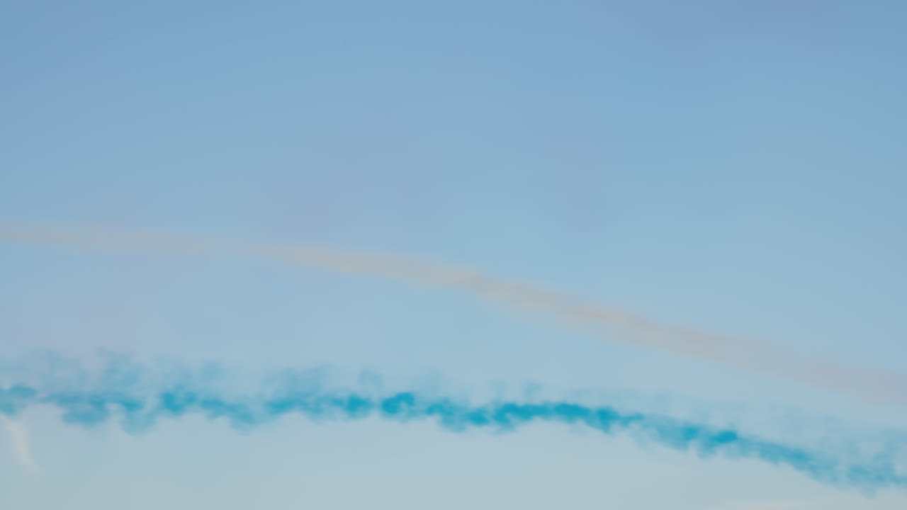 Aerei di linea che volano con scie di fumo rosse e blu nel cielo sereno