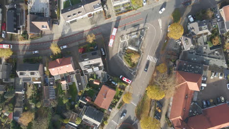 Antena-De-Arriba-Hacia-Abajo-Del-Autobús-Que-Sale-De-La-Pequeña-Estación-De-Autobuses-En-Un-Pequeño-Pueblo-En-Otoño