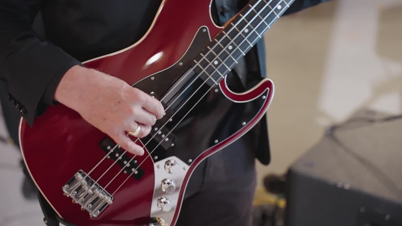 White Man's Hand Strumming Red Electric Bass Guitar Close Up