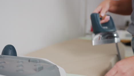 close up of dress maker picking iron, placing on apparel, steam visibly rising, removing wrinkles, ensuring neat finish, highlighting professional pressing skill, focusing on careful technique