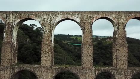 drone flight shot crossing one of the arches of the historic site "arcos del sitio" in tepotzotlán, state of mexico, mexico