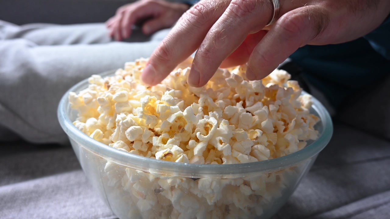 Uomo che mangia popcorn sul divano