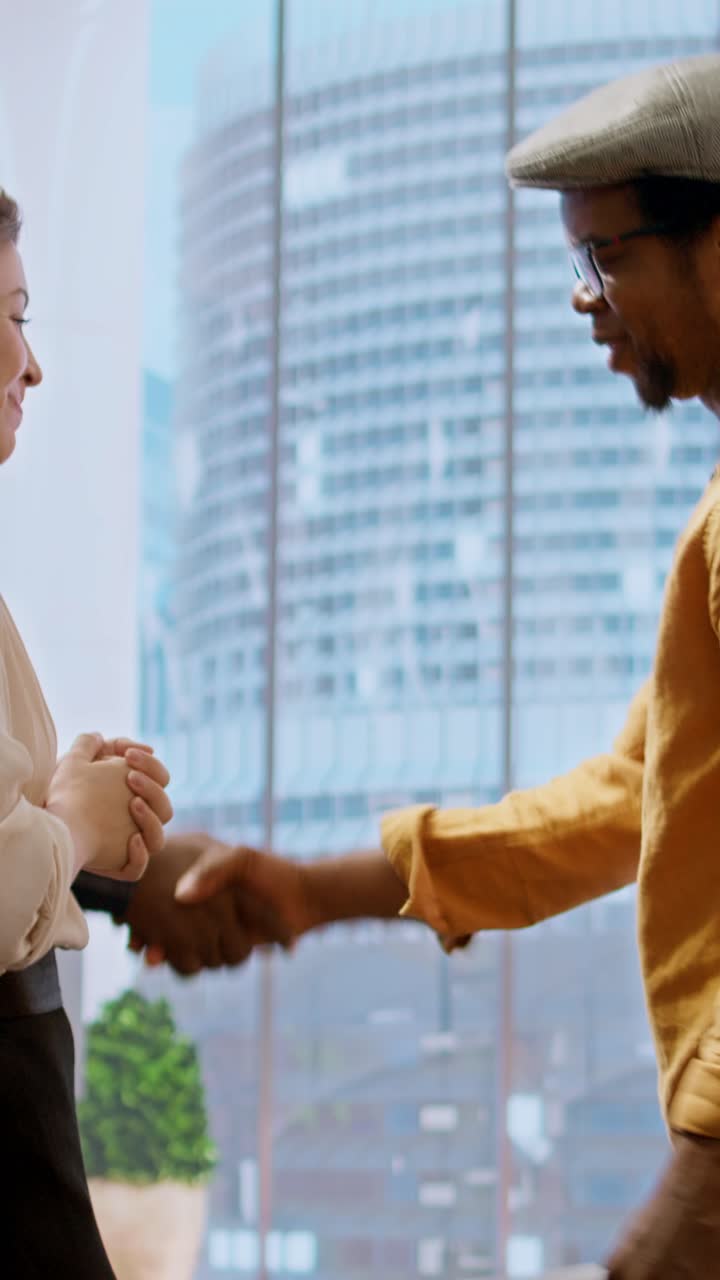 Woman and Man Shaking Hands in Modern Office with City View