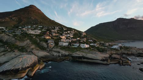 Expensive-oceanfront-mansions-on-mountain-hill-at-Llandudno-Beach-in-Cape-Town,-aerial