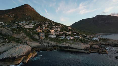 expensive oceanfront mansions on mountain hill at llandudno beach in cape town, aerial