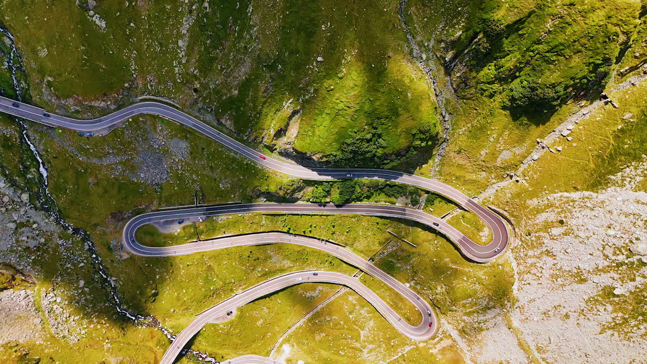 Verdant rock with the challenging mountain highway. Transfagarash road in the Carpathian Mountains, Romania from drone