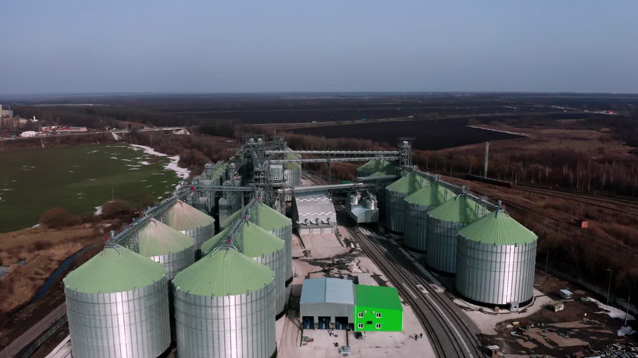Metal silos on field aerial view. Large containers for storing and processing grains. Silver grain elevators in farmland. Storage tank view from above. Silo with grain.