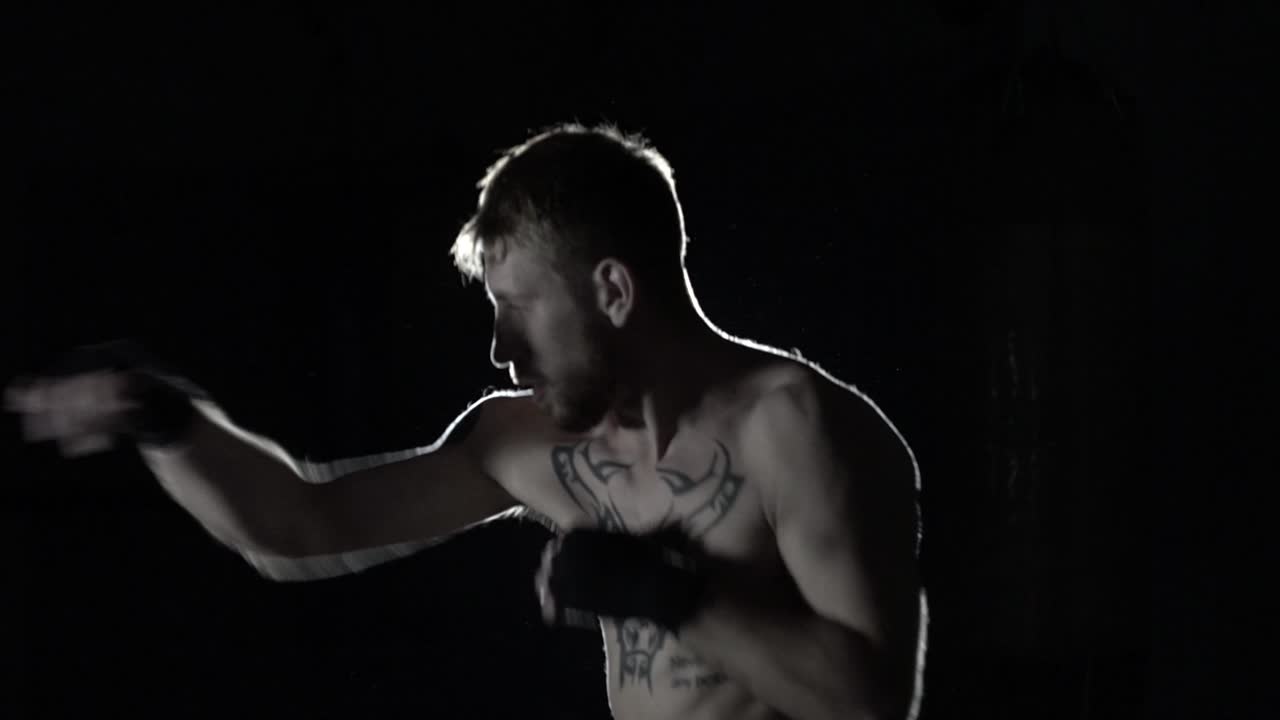 boxeador en cámara lenta contra un reflector y humo