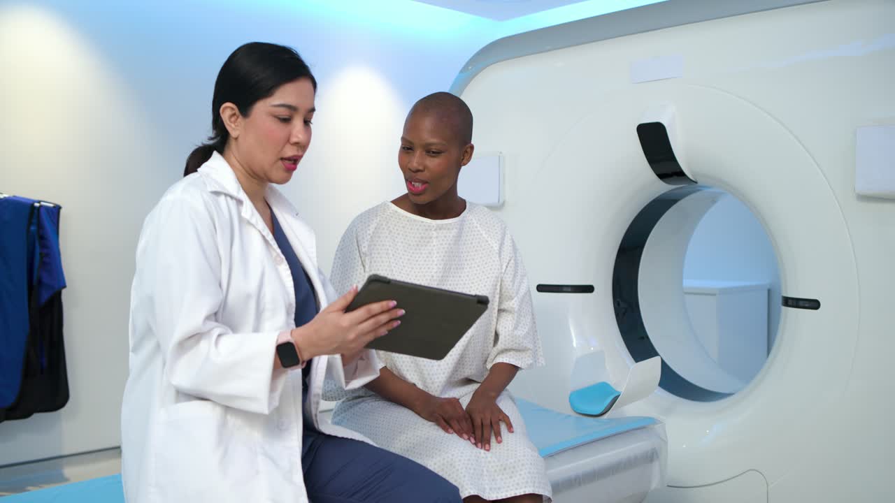 Clinico ispanico che gira il tablet, esaminando la TAC mentre un paziente afroamericano lo tocca, sorridendo