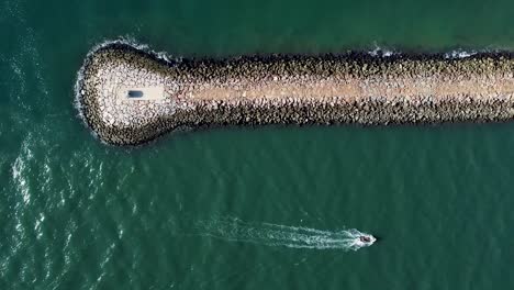 Ship-sailing-alongside-a-breakwater-wall-jetty-in-the-Atlantic-Ocean-on-the-south-of-Portugal