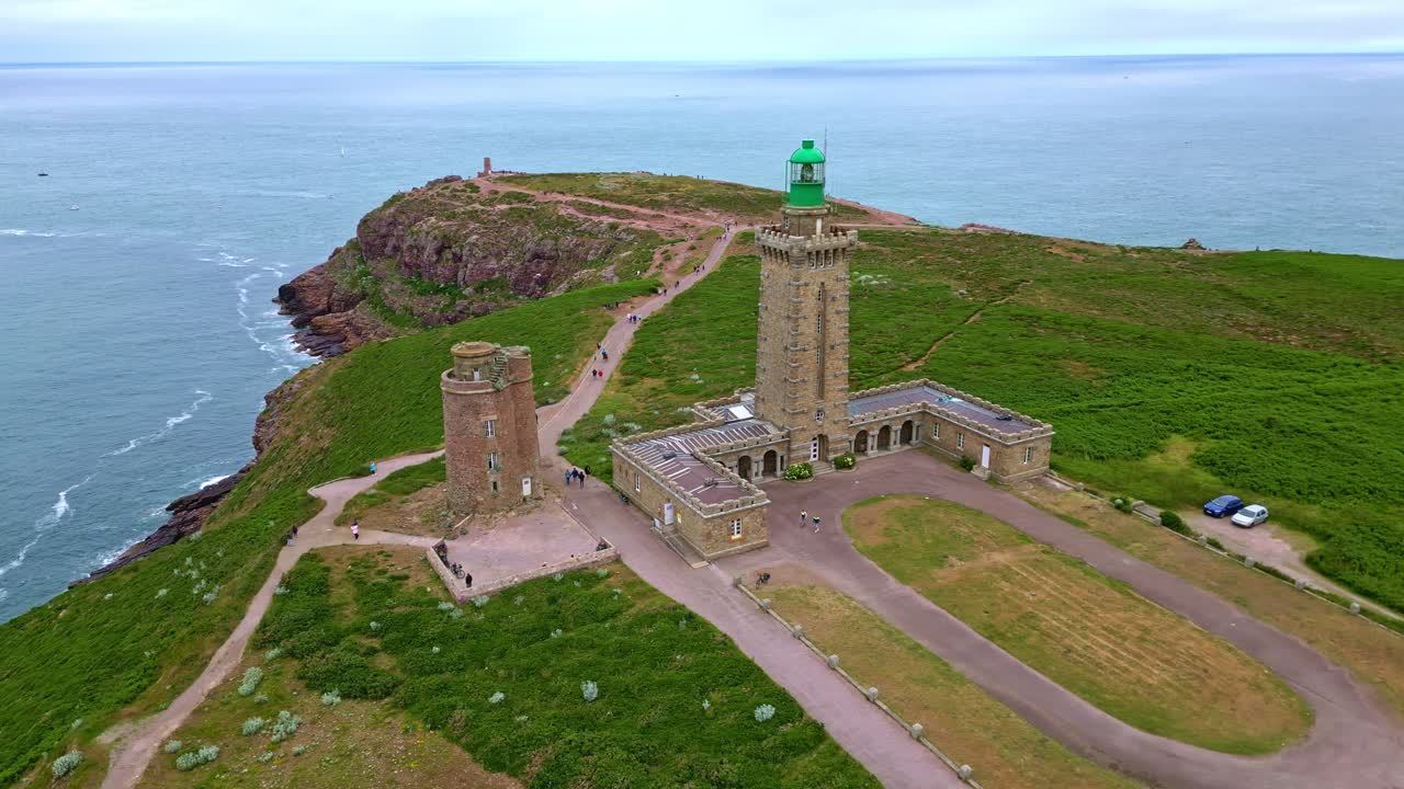 Side aerial view of Cap Fréhel lighthouse, with cliffs, rock outcrop and coastal paths. Brittany in France