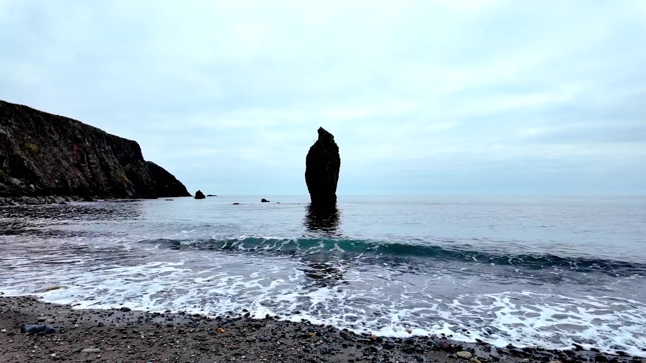 Irlands episke steder: Ballydwane strand ved skumringstid med blide bølger og en dramatisk havstabel.