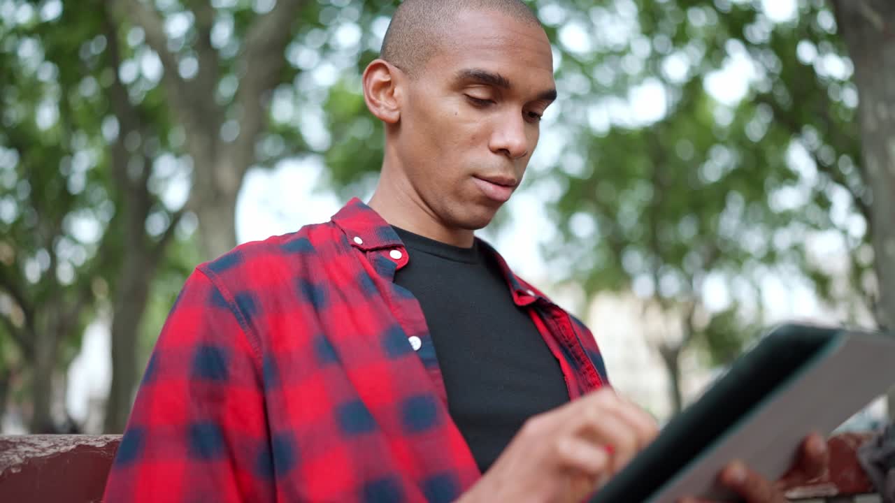Confident bald man typing on digital tablet and looking at camera