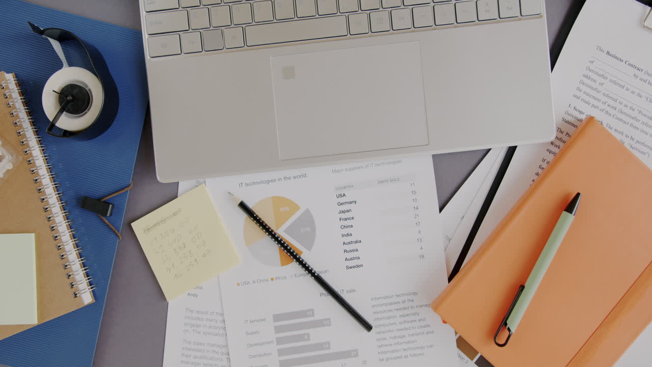 Busy Office Workspace with Laptop, Documents, and Charts