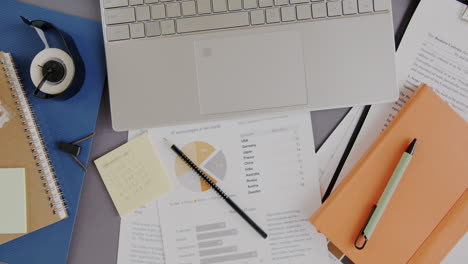 busy office workspace with laptop, documents, and charts