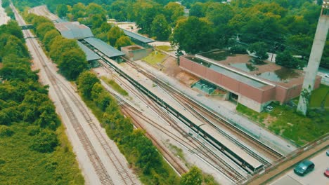 Drohnenaufnahmen-Eines-Zuges,-Der-Unter-Einer-Brücke-Voller-Verkehr-In-Einen-Bahnhof-Fährt