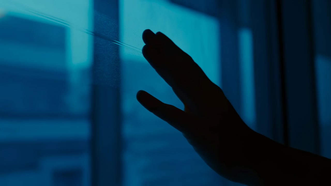 Urban skyline with tall buildings visible through a window, hands reaching out to touch the glass, evoking curiosity or longing from a first-person perspective inside the building. This evi.
