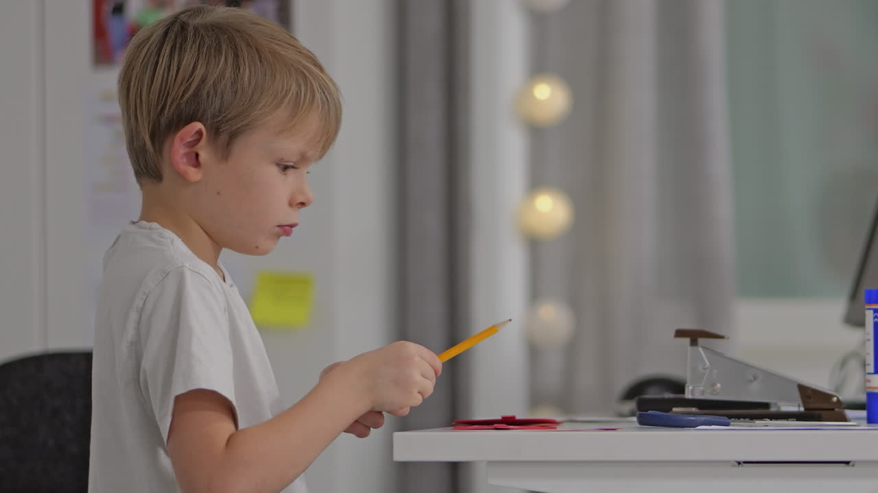 молодой мальчик концентрируется на написании за своим столом в современной, уютной комнате с теплым освещением