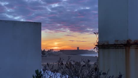 Riesiger-Sonnenaufgang-über-Dem-Strand-Von-Carcavelos,-Gesehen-Zwischen-Zwei-Schornsteinen