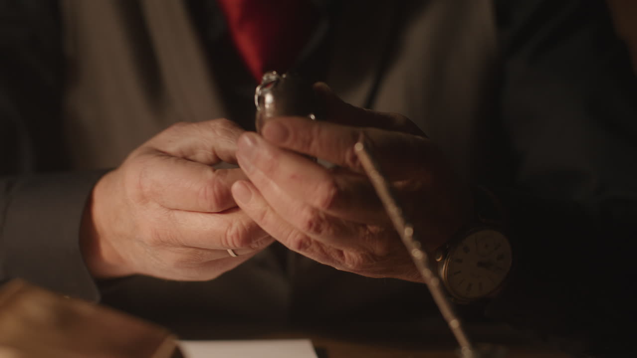Older passionate man evaluates an old silver skull watch in his office at night