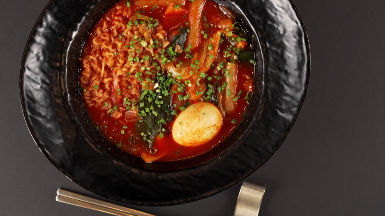 A flavorful bowl of chewy rice cakes, springy noodles, and rich, spicy broth, topped with fish cakes, scallions, and a soft-boiled egg. 쫄깃한 떡과 면, 진한 매콤한 국물에 어묵, 쪽파, 반숙 계란을 더한 풍미 가득한 한 그릇.