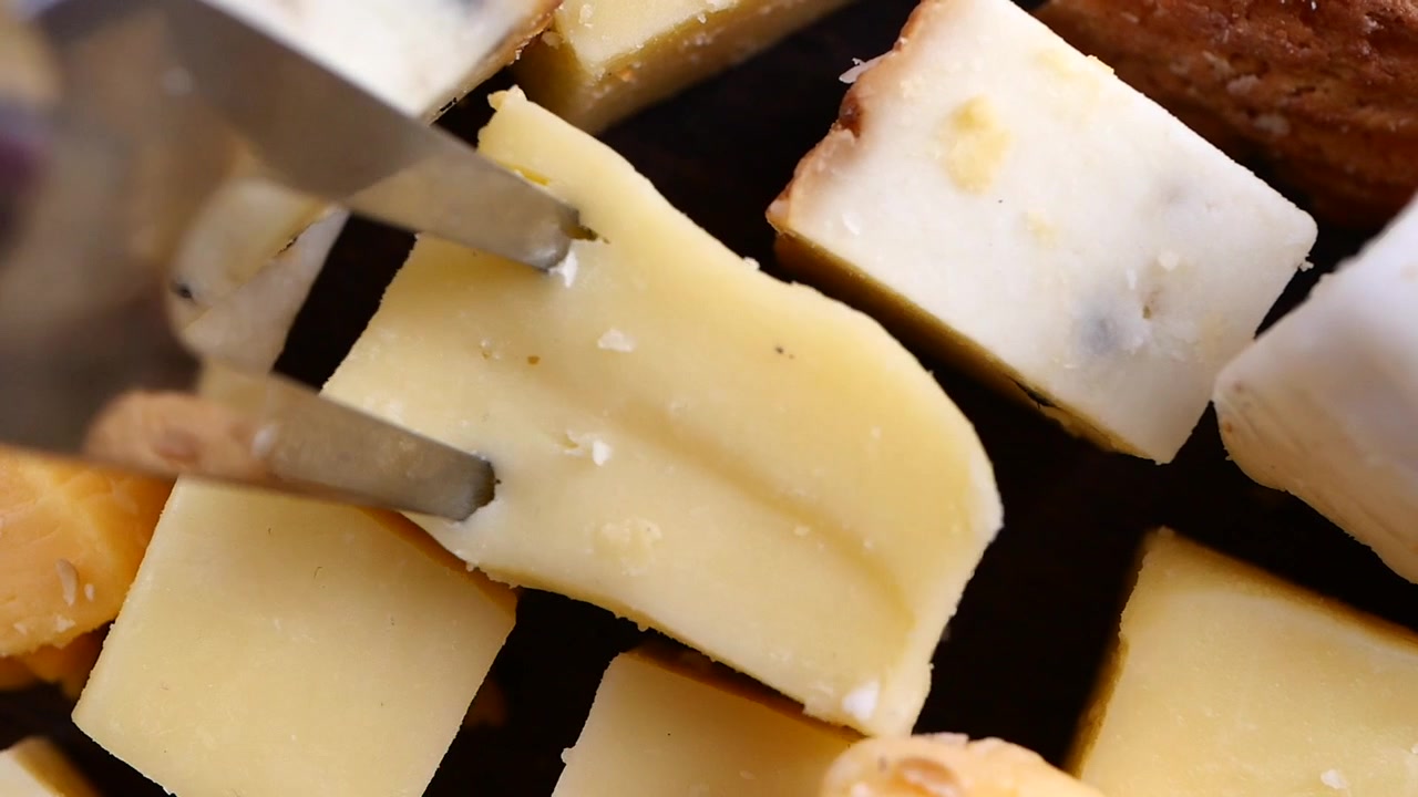 Eine Gabel nimmt einen köstlichen Käsewürfel von einer Gourmetplatte