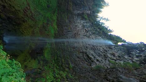 Vertical-shot-of-a-waterfall-with-a-sharp-rock-wall-cliff-face