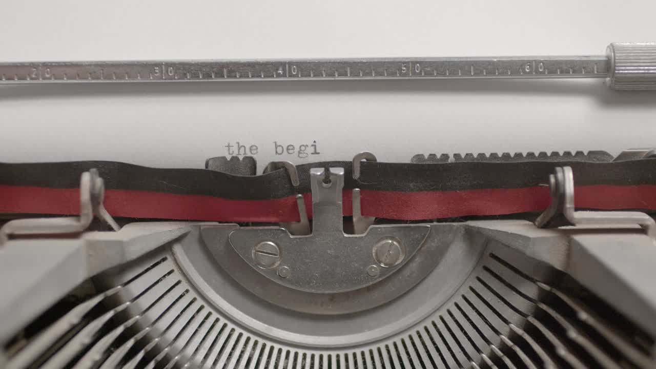 Closeup of a typewriter machine writing The Beginning