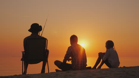 three teenagers are fishing on the shore of the lake at sunset happy childhood concept  4k video