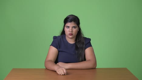 young overweight beautiful indian businesswoman against green background