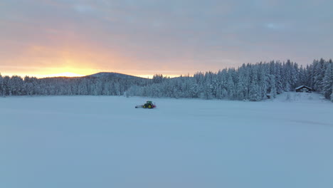 Tracking-Norbotten-snow-blower-clearing-woodland-ice-drifting-track-aerial-view-golden-sunrise