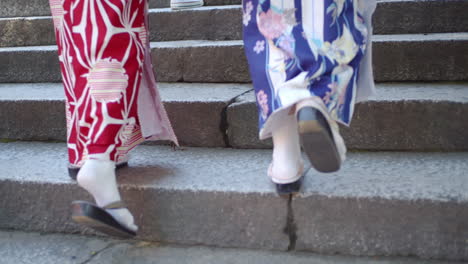 beautiful girls walking in traditional kimono wearing wooden sandles going up the stairs in kyoto, japan soft lighting