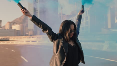 young woman holding smoke grenades in city street protesting with arms raised