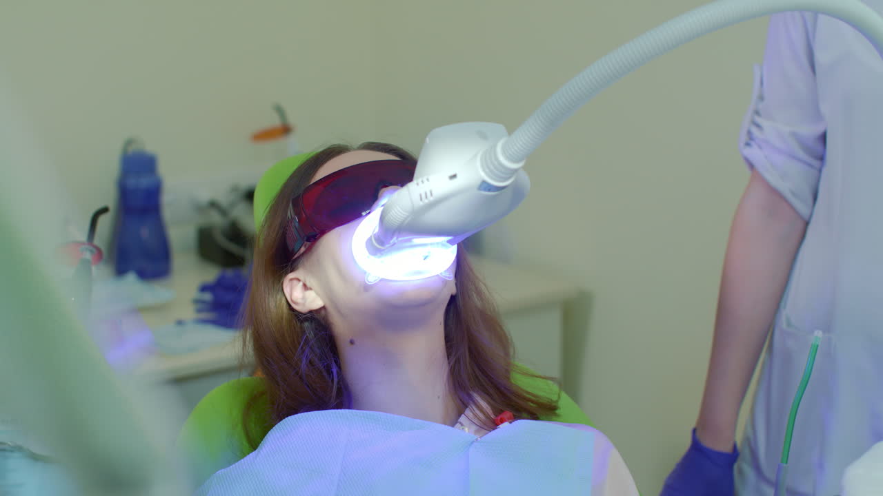Diş kliniğinde diş beyazlatma işlemi. LED beyazlatma ışığı ile dişlerin beyazlatılması.