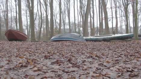 Low-dolly-of-old-boats-in-middle-of-forest