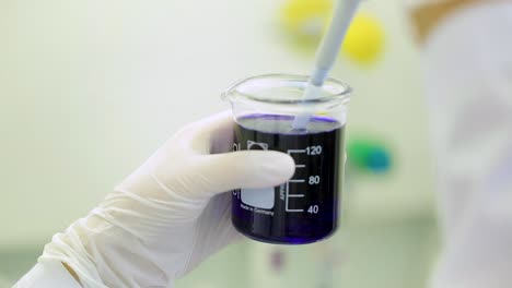 scientist transferring blue liquid in a beaker